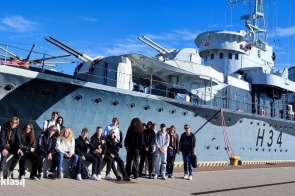  Na zdjęciu widoczna jest grupa uczniów stojących przed okrętem-muzeum ORP "Błyskawica" w Gdyni. To jeden z najstarszych zachowanych niszczycieli na świecie, będący ważnym symbolem historii polskiej marynarki wojennej. Uczniowie biorą udział w wycieczce edukacyjnej organizowanej w ramach programu "Podróże z klasą", podczas której mieli okazję poznać bogatą historię okrętu i zobaczyć jego wnętrza.