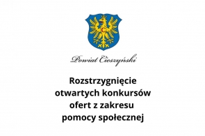 Na grafice widoczny jest herb Powiatu Cieszyńskiego, który przedstawia żółtego orła z koroną na niebieskim tle. Pod herbem znajduje się napis „Powiat Cieszyński”, a poniżej tekst informacyjny: „Rozstrzygnięcie otwartych konkursów ofert z zakresu pomocy społecznej”. Tło grafiki jest białe.