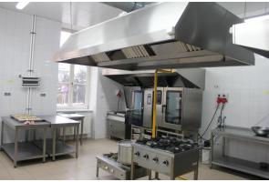 Nowoczesna pracownia gastronomiczna z profesjonalnym wyposażeniem; widoczne kuchenki gazowe, piekarniki, stoły robocze i okap w sali ZSEG w Cieszynie.