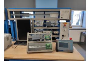 Stanowisko dydaktyczne z modułami automatyki przemysłowej, panelem HMI, sterownikiem PLC i komputerem. W tle okno i kaloryfer w Zespole Szkół Technicznych w Cieszynie.