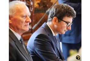 Dwaj uczestnicy konwentu starostów w garniturach siedzą obok siebie i słuchają obrad.