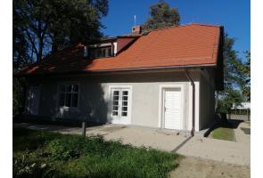 Odnowiony Domek Ogrodnika, siedziba Muzeum im. Zofii Kossak, z czerwonym dachem i utwardzonym dojściem do wejścia.