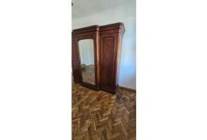 Ciemna drewniana szafa z centralnym lustrem w pomieszczeniu z parkietem.