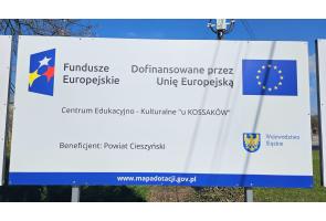 Tablica informuje o dofinansowaniu przez Unię Europejską projektu „Centrum Edukacyjno-Kulturalne u Kossaków”; beneficjentem jest Powiat Cieszyński.