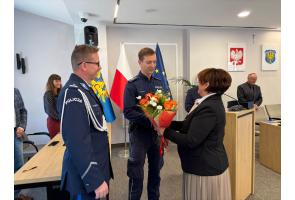 Aspirant Rafał Górczyński odbiera bukiet kwiatów podczas uroczystości wyróżnienia w sali Rady Powiatu Cieszyńskiego.