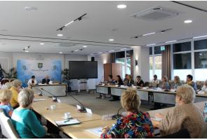 Uczestnicy VIII sesji Rady Seniorów Powiatu Cieszyńskiego podczas obrad przy stołach w sali konferencyjnej; z przodu widoczny napis „Powiat Cieszyński”.