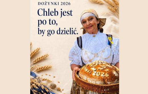 Beżowa grafika dożynkowa z kłosami zbóż i napisem „Dożynki 2026. Chleb jest po to, by go dzielić.” Po prawej stronie stoi Janina Żagan Starosta Cieszyńska w stroju regionalnym, trzymająca w wiklinowym koszu duży, ozdobny bochen chleba z napisem „Dożynki 2026”.